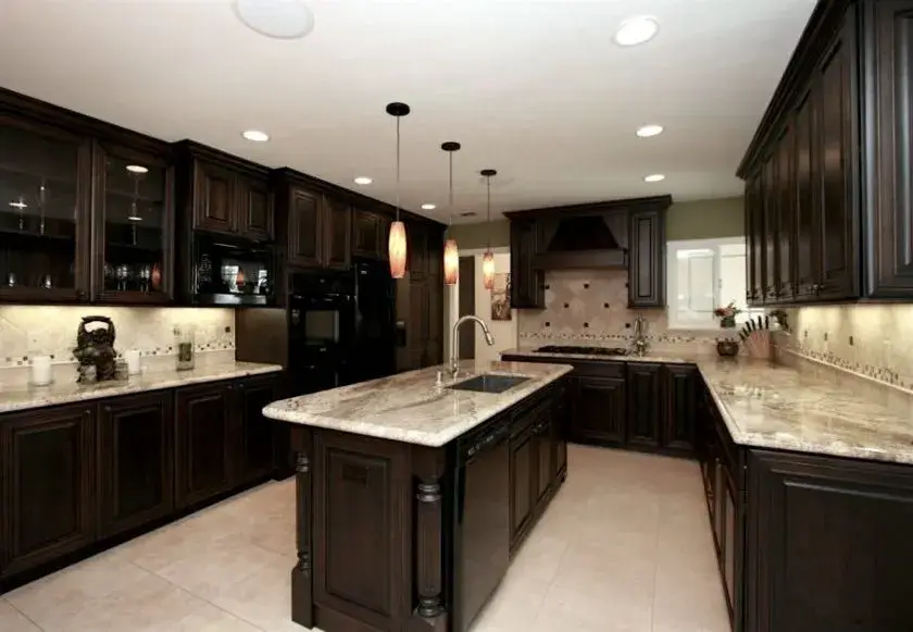 A classic kitchen with marble countertops and dark wood cabinets